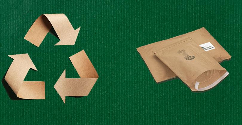 Recycling Zeichen aus Karton auf grünem Grund, daneben Papier-Versandtaschen