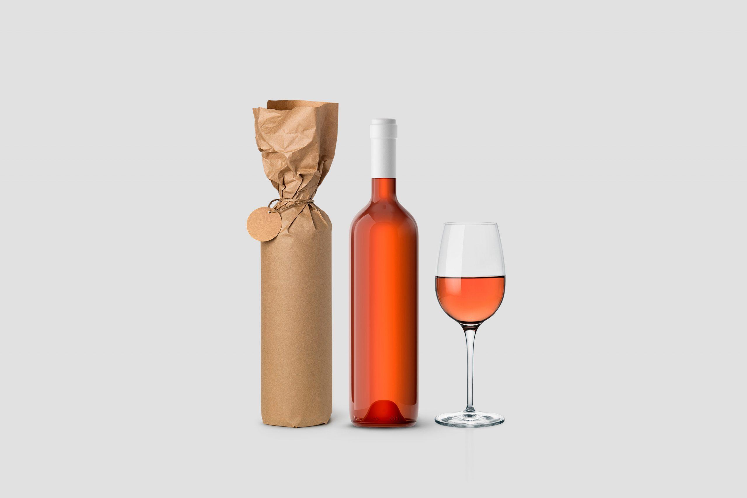 Weinflasche in Papier eingewickelt mit Etikett und Glas auf weissem Hintergrund
